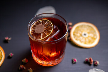 Whiskey sour cocktail decorated with dried orange on a black table