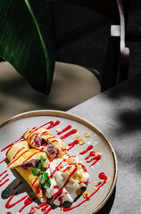 Delicious crepes with berry sauce and whipped cream on a dining table