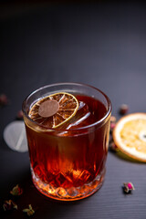 Whiskey sour cocktail decorated with dried orange on a black table
