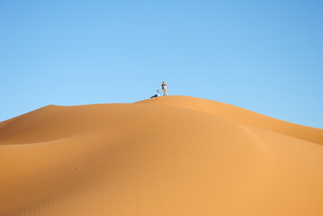 A desert landscape with a blue sky and footprints in the sand