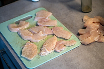 Raw chicken fillets seasoned with pepper on chopping board
