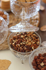 Lit candles, cookies, chocolate, nuts, tea, wine, pumpkins, books, reading glasses and autumn leaves on the table. Autumnal hygge at home. Selective focus.