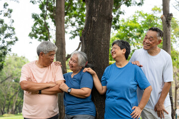Four older adults enjoy a cheerful moment together in a lush outdoor setting. Their smiles and relaxed poses highlight themes of friendship, active aging, and joy of social connection in later life.