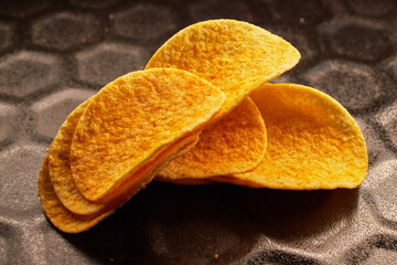Close-up of several potato chips on a black baking tray