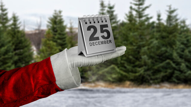 Santa hands show a calendar of 25 December with a snowy field background. Mockup or Copy space. Holiday greetings or winter themes. Concept of the Merry Christmas celebration