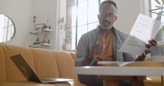 Mid Adult Man Working from Home Looking at Paper Finical Statements