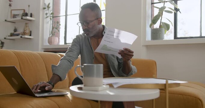 Mid Adult Man Working from Home Looking at Paper Finical Statements
