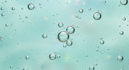 Close-up of clear bubbles floating in light blue liquid with subtle background reflections