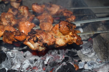 BBQ Meat on Coals: Sizzling grilled meat on a skewer, cooked to perfection over hot coals, ready to be enjoyed. A mouthwatering visual experience.