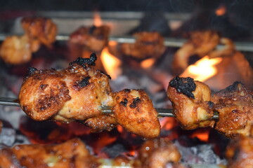 Succulent Grilled Chicken: Juicy chicken pieces are rotating over glowing hot coals, the aroma of smoky, grilled chicken fills the air, promising a mouthwatering meal.