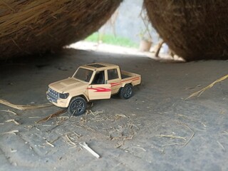 A beige, 1:32 scale die-cast model pickup truck with opening doors and pull-back action is pictured on a concrete surface. 