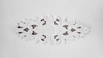 A traditional Indonesian floral wood carving (ukiran) painted white and isolated on a light gray background. Concepts of cultural decoration, craftsmanship, texture, heritage, furniture design.