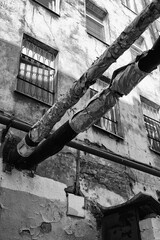 Monochrome photo with two dilapidated sewer or water pipes in the old city area vertical orientation