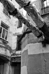 Black and white photo with two outdated and foil-wrapped pipes against the background of an old house with windows vertical orientation