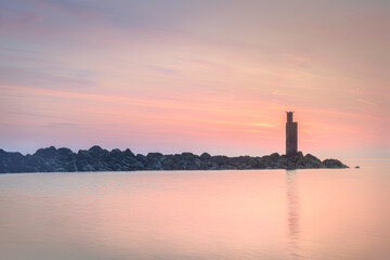 The composition balances the rocks with the smooth, reflective water, the colorful sky and the setting sun