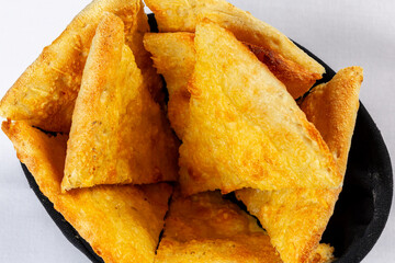 Foccacia or pita. Triangular pieces of lightly browned Pita, Naan, or flatbread served in a black fabric basket on a white background.