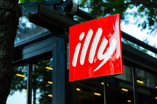 Illy logo. Red and white sign displaying the logo of Italian coffee company Illy, hanging outside a cafe or coffee shop.