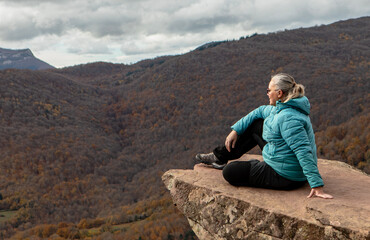Naklejka premium Serenity found on a rocky ledge with breathtaking mountain views and autumn colors in the distance