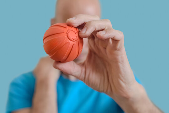 Man showing small ball for massaging stiff muscles and relieve spinal pain. Man holds massage ball for myofascial release and muscle pain relief therapy