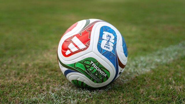 Bangkok, Thailand - 18 November 2025: Adidas "Trionda" the official match ball for Fifa World Cup 2026 that co-host in America. The ball is placed on grass pitch with football stadium component.