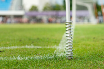 Football field corner area with line and flag post with beautiful green grass ground and stadium environment component as background.