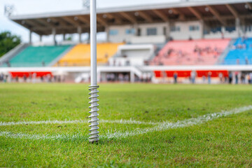 Football field corner area with line and flag post with beautiful green grass ground and stadium environment component as background.