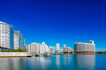 Fototapeta premium Brickell Miami 2025. Scene of water and coastal highrise condominiums on a deep blue sky