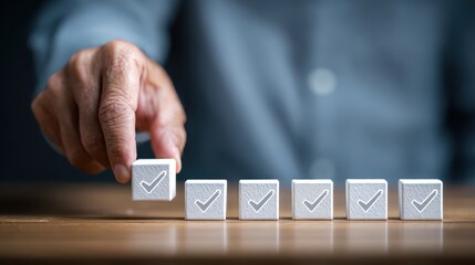 Hand of a person placing cube with checkmark symbol on wooden table, representing successful completion of tasks and achievements in work or project goals