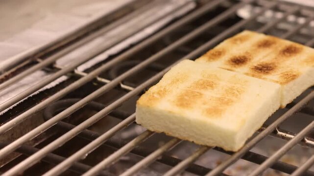 Tasty white bread grilling on a barbecue grate. Appetizing golden grill marks and a crispy texture. Perfect for advertising healthy breakfast, cafes, restaurants, proper nutrition concepts