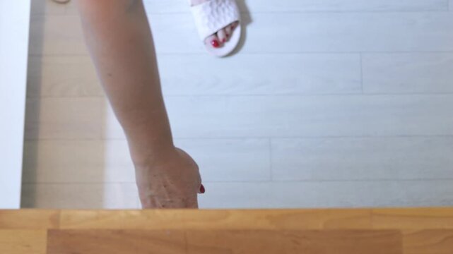 A woman is stacking plates into a wooden kitchen drawer. Top view.