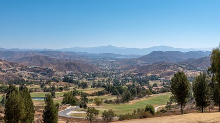 Obraz premium Scenic View of Rolling Hills and Golf Course Surrounded by Lush Greenery Under Clear Blue Sky in a Serene Landscape