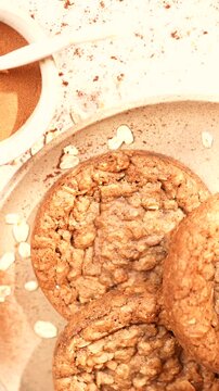 A plate of cookies with a white bowl of sugar and cinnamon next to it. The plate of cookies is topped with a generous amount of cinnamon, giving it a warm and inviting appearance