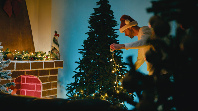 Man Decorates Christmas Tree While Dancing with White LED Lights