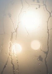 Abstract sunlit scene through misty glass with water droplets creating a soft, warm, atmospheric backdrop for creative projects
