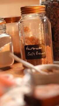 A jar of soft brown flour sits on a table. The label on the jar says "fast trade"