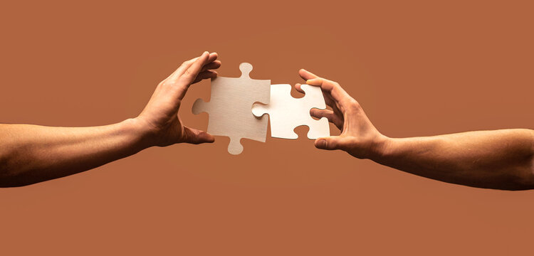 Hand connecting jigsaw puzzle. Man hands connecting couple puzzle piece. Closeup hands of man connecting jigsaw puzzle. Two hands trying to connect couple puzzle