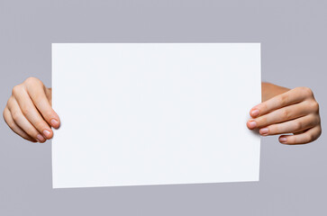 Copy space for your text. Man's hands holding empty board isolated on gray background. Closeup. Close up of a woman hand holding empty blank white board, your text here concept