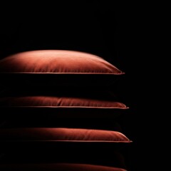 Luxurious velvet cushions stacked in soft light, creating deep shadows that emphasize the plush, decadent texture and inviting comfort ,indulgence ,heap ,close up