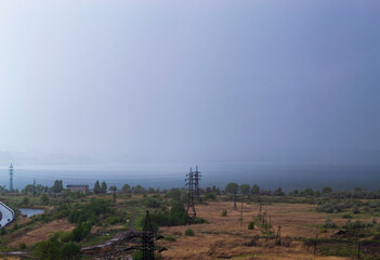 Rainstorm over lake and industrial cityscape