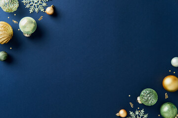 Corner Christmas composition with shiny gold and green Xmas decorations on navy blue background....