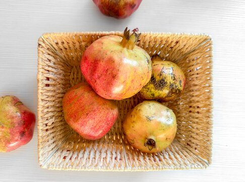 Imperfect Pomegranates in a Woven Basket on Light Background, Top View, flat lay. anemia 