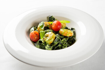 Gourmet spinach tagliatelle pasta with plump prawns, burst cherry tomatoes, and fresh basil, served in a white bowl. Bright, healthy Italian seafood meal
