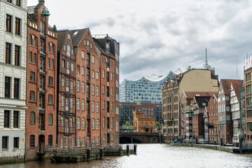 Historic warehouse buildings along the canal with the Elbphilharmonie in the distance