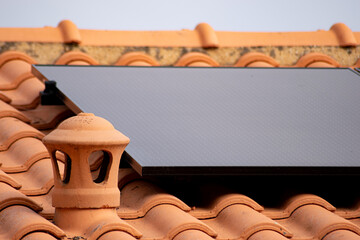 Gros plan sur une toiture avec lanterne en terre cuite devant un panneau solaire