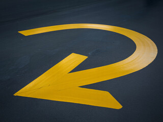 Bold yellow arrow painted on dark asphalt directs traffic flow, guiding movement and indicating direction clearly.