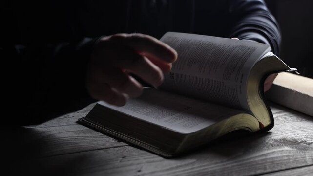 person studying a book, flipping through pages to find information that you are looking for. scrolling through the bible to find a passage 