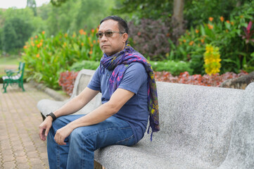 Thoughtful Mature Man Sits on Park Bench in Serene Outdoor Garden
