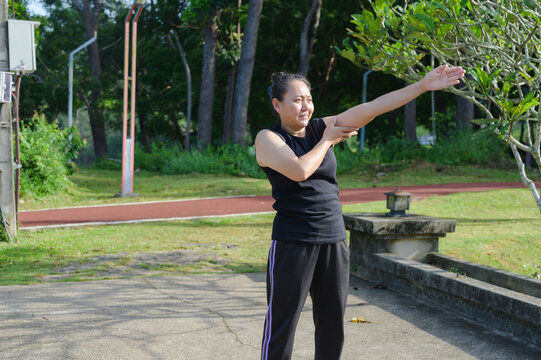 Asian Woman Stretching Outdoors in Park for Healthy Lifestyle and Fitness