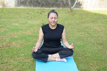 Peaceful Woman Practicing Yoga Meditation Outdoors on Green Grass Mat for Wellness