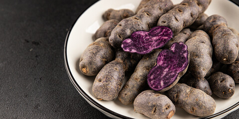 Purple potatoes raw fruit blue potatoe vegetable dish fresh gourmet food background on the table rustic food top view copy space keto and paleo diet vegan and vegetarian food